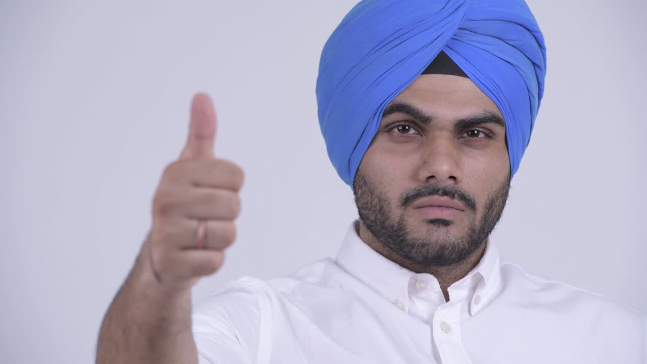 Volto di un giovane uomo Sikh indiano barbuto e felice con turbante.