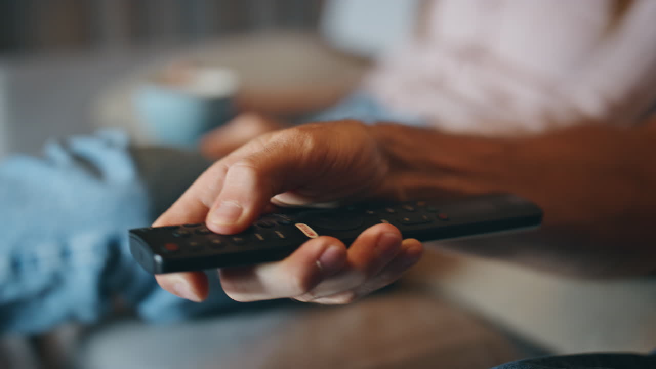 Boyfriend hand holding tv remote home closeup. Couple choosing television shows