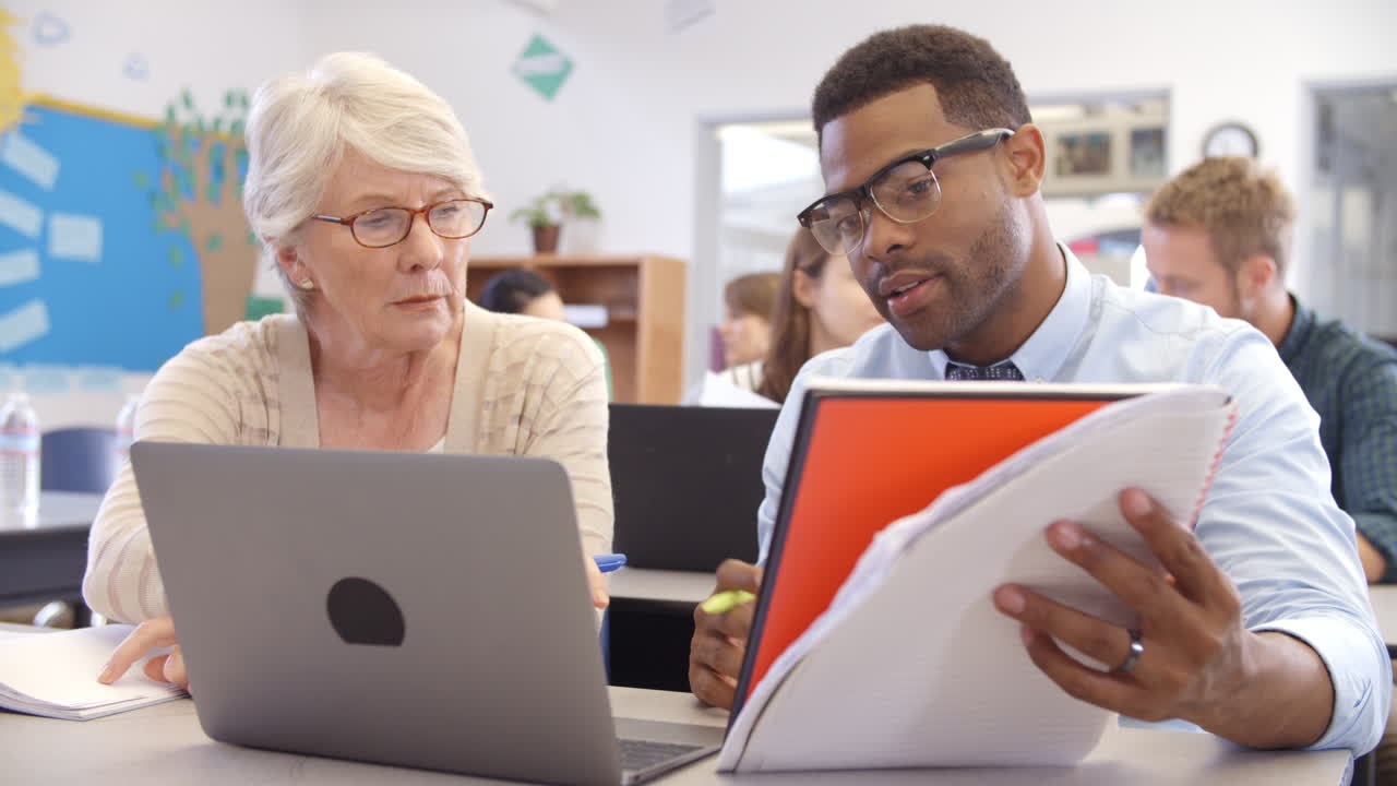 Teacher and student using laptop at an adult education class
