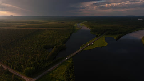 AERIAL:-traffic-on-a-bridge-in-middle-of-lakes-of-Lapland,-moody,-summer-sunset