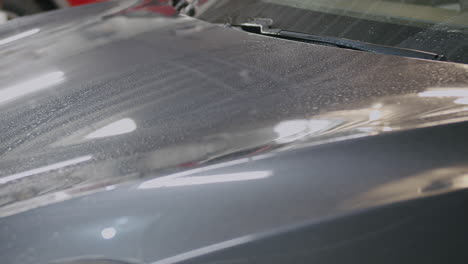 Caucasian-male-hand-using-yellow-chamois-to-dry-off-bonnet-at-car-wash