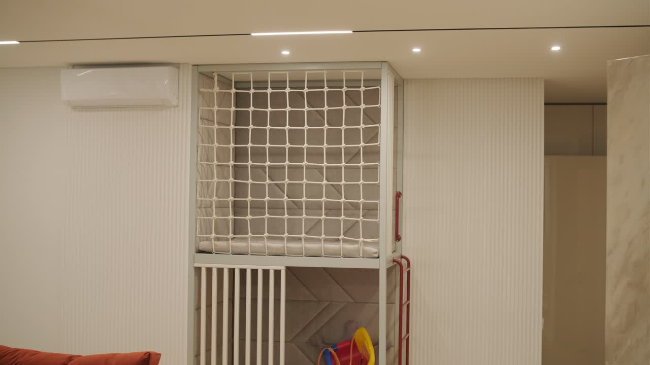 설명: 은 오렌지색 소파와 플러시 베개가 있는 쾌적한 방 모이, 장난감과 다채로운 삼자전거가 있는 어린이 놀이 공간, 색 안전 게이트로 보호됩니다.