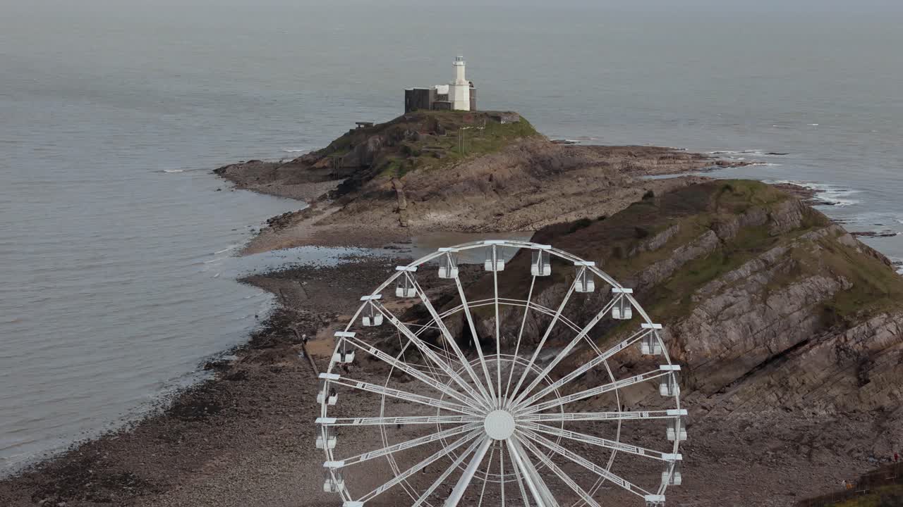 The Big Wheel rotating with a Mumbles Lighthouse at background in Mumbles Pier Swansea of England. Aerial view.