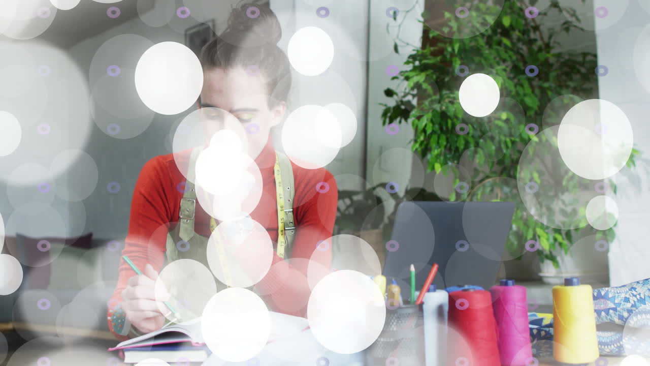 woman sketching in notebook in craft room, with floating bokeh lights and colorful thread spools