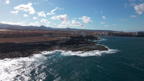 drone move forward over the ocean in the foreground is gran canaria sea cliff waves flow over the stone beach at gran canaria