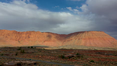 Aerial-shot-of-Kayenta-Art-Village-and-the-surrounding-areas,-going-over-a-road-with-a-car-on-it