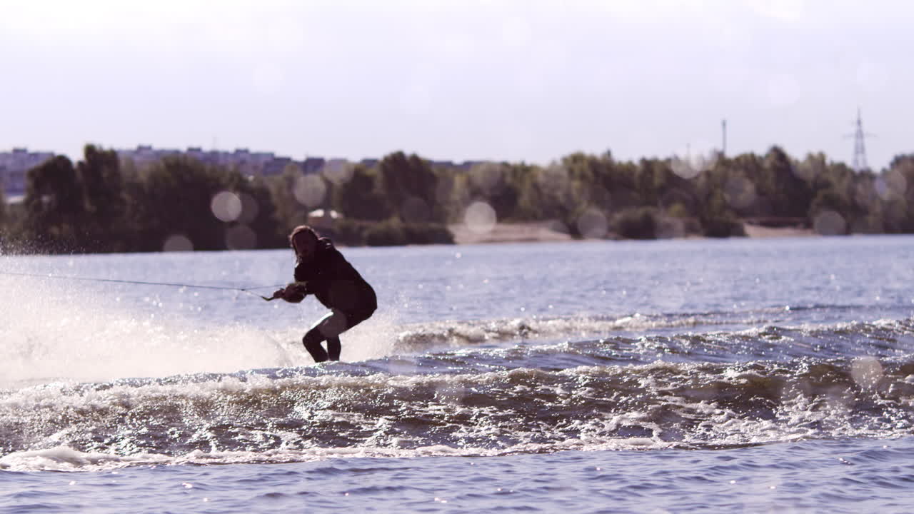 un tipo montando un wakeboard en un río ancho.