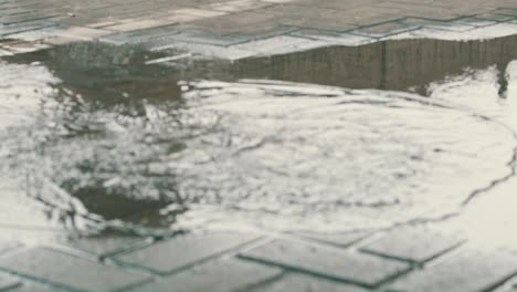 Person-with-high-leather-boots-steps-into-a-puddle-of-water