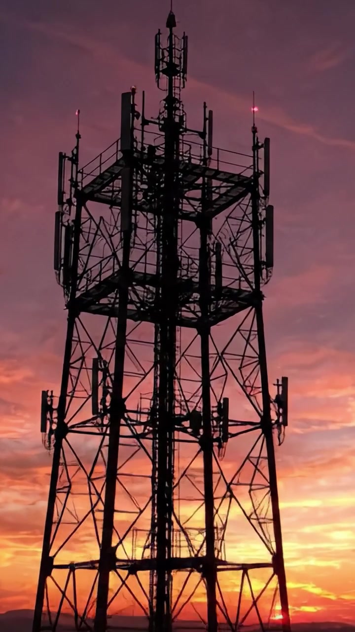 Silhouette drammatiche al tramonto: Una torre cellulare si erge alta contro un cielo vibrante, mostrando le comunicazioni moderne in mezzo alla bellezza della natura