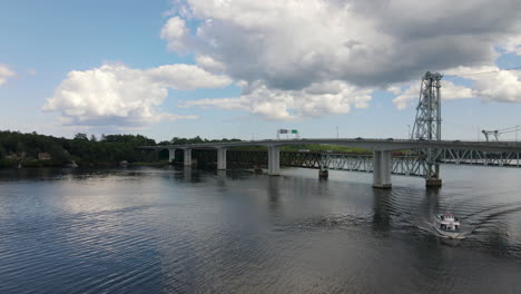 drone footage of a tour boat under the bridge at bath city in maine