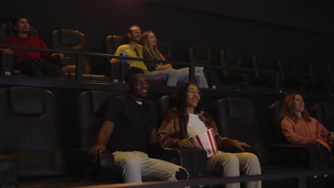 mixed raced young couple sitting in movie theatre and watching film