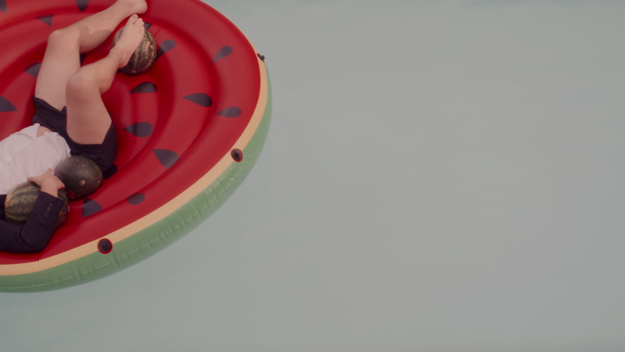 Man Relaxing on Watermelon Inflatable Pool Float