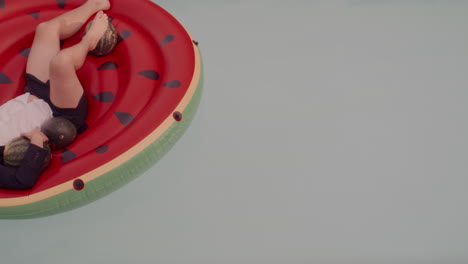 man relaxing on watermelon inflatable pool float