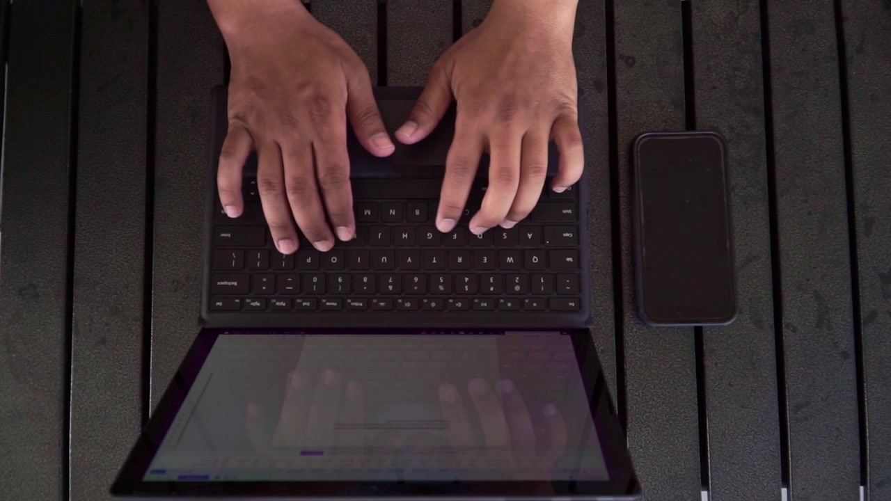 Hands of human beings placing smartphone next to laptop on black table. modern multitasking and remote work concept.