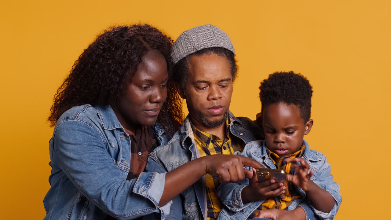 Una allegra famiglia afroamericana che scatta foto sullo sfondo giallo