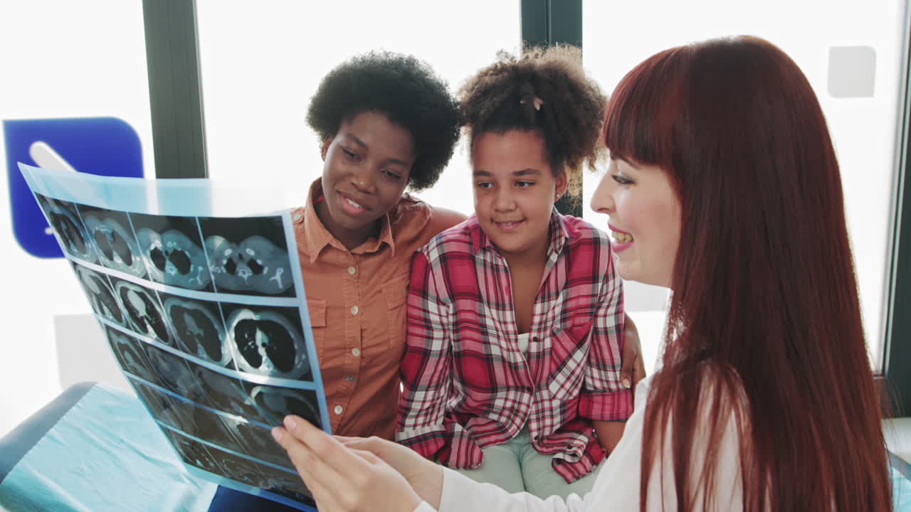 Pediatrician with a mixed race child female pediatrician examines childs xray with african american