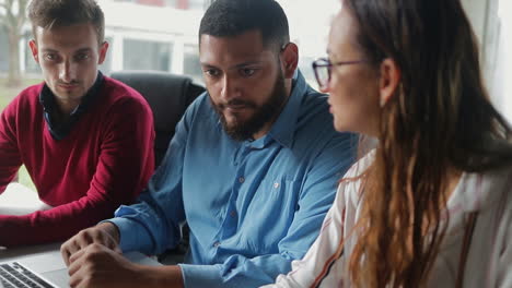 empleados concentrados trabajando mientras están sentados a la mesa en la oficina.