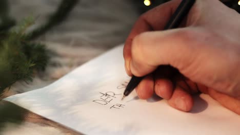 hand writing a christmas letter for santa with spelling mistakes on an empty piece of paper