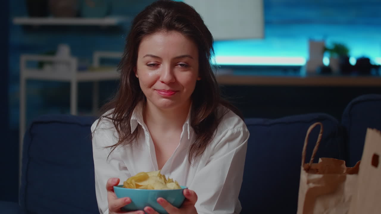 Portrait of smiling woman holding bowl of chips in hands