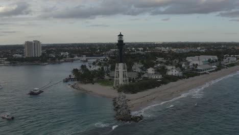 Toma-Aérea-En-órbita-Alrededor-De-Un-Faro-Que-Muestra-La-Bahía,-El-Océano-Y-Los-Edificios-Que-Lo-Rodean