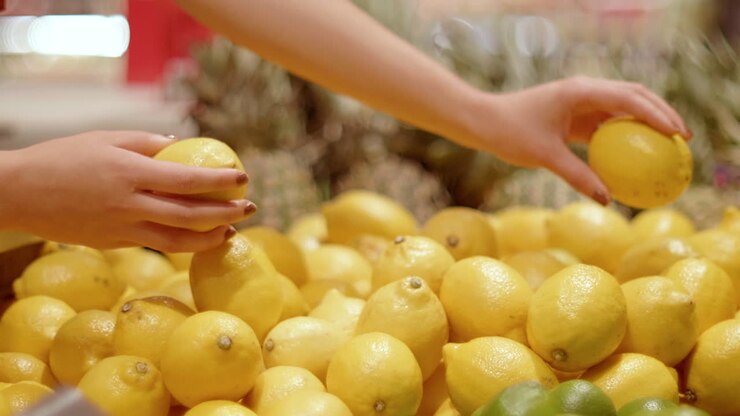 Mani di donna che sistemano i limoni in un negozio di alimentari.