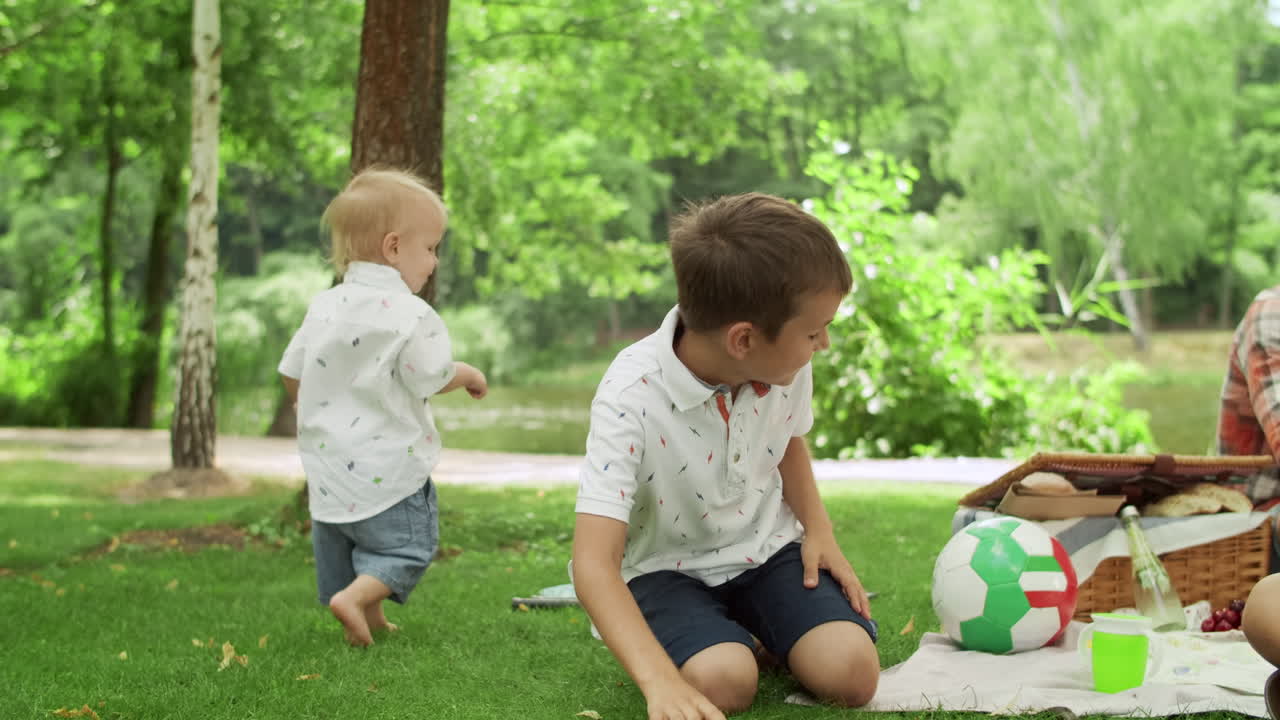 Man sitting on blanket with children in park. Children playing with soap bubbles