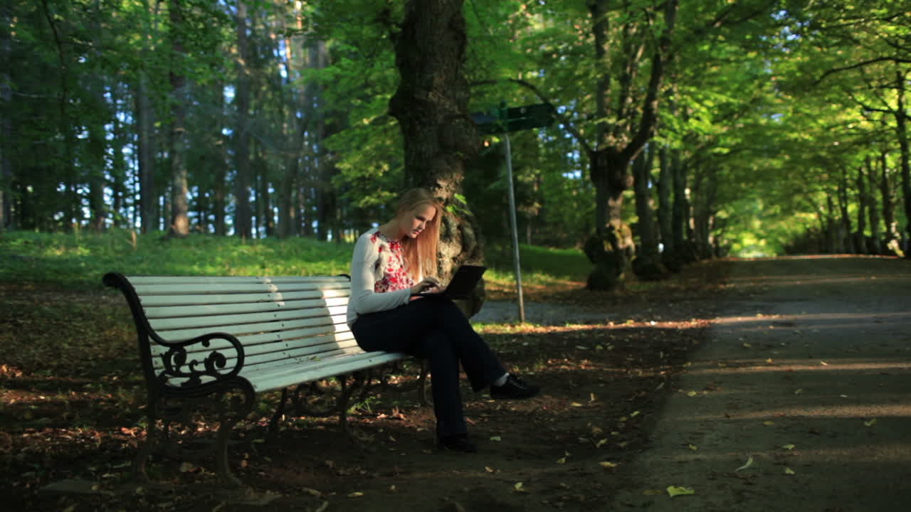 молодая женщина с ноутбуком в парке