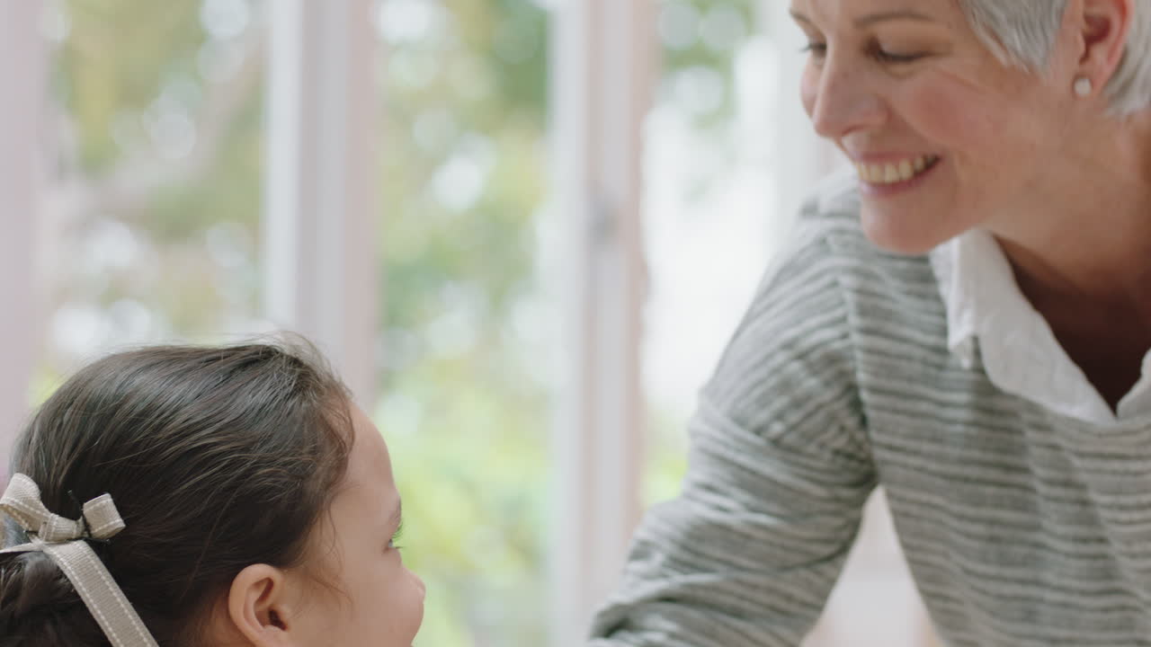 행복한 할머니는 작은 소녀를 이마에 부드럽게 키스하고 손녀에 대한 사랑을 보여주고 자랑스러운 할머니는 집에서 손자에 대한 애정을 나누고 있습니다.