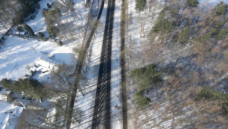 top down aerial of empty road running through forest in winter