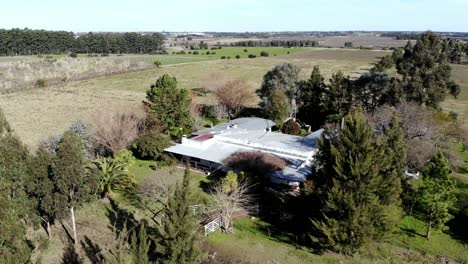 aerial-video-of-a-house-in-the-countryside,-plantations-and-trees-on-a-clear-day