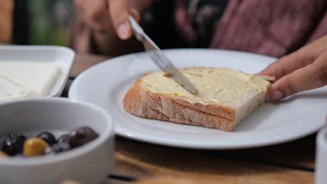 mujer esparciendo mantequilla sobre el pan para el desayuno