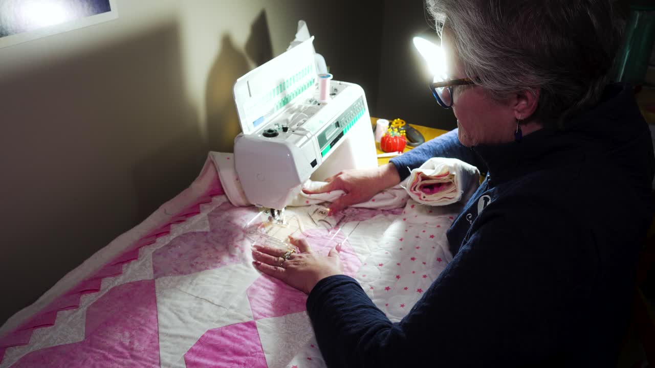 Senior woman using a sewing machine to stitch a pattern on a handmade quilt