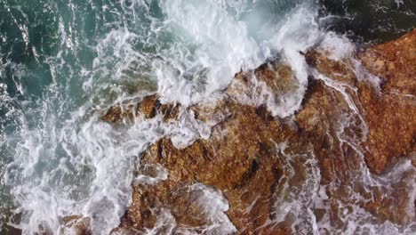 Powerful-waves-flowing-over-rocky-coastline,-top-down-view