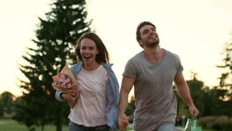 Pareja-Feliz-Con-Flores-Corriendo-En-El-Parque-De-Verano.-Pareja-Enamorada