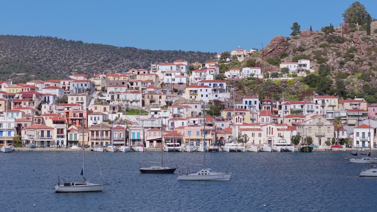 Drone footage of Poros Island seafront, capturing the traditional architecture and charming houses along the harbor with stunning views of the Aegean