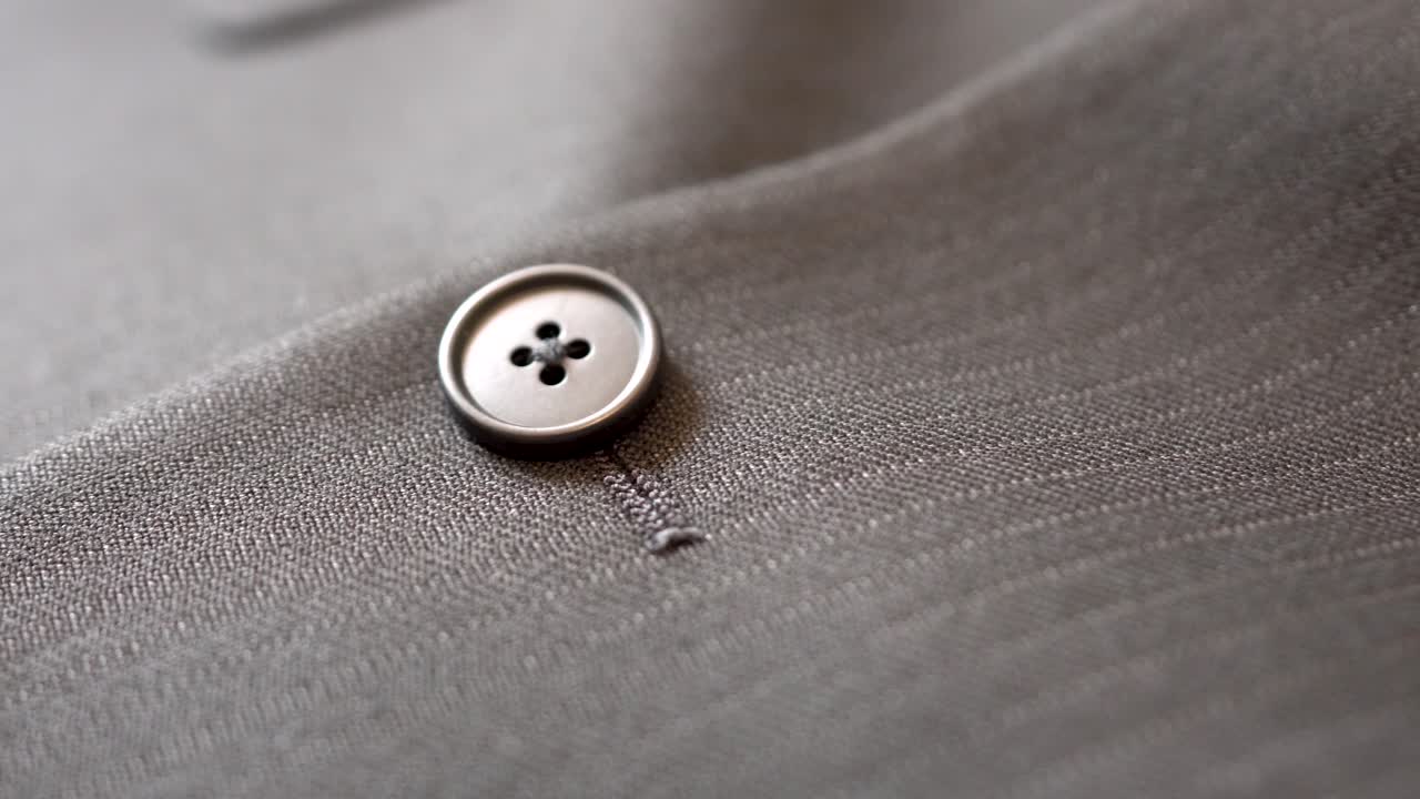 cierre parte de los detalles de diseño de tela de traje de hombre, chaqueta de rayas rectas gris oscuro, enfoque en el botón