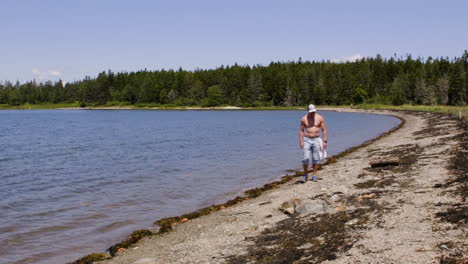 adulto, blanco, hombre sin camisa caminando por una playa de nueva inglaterra en una tarde de verano