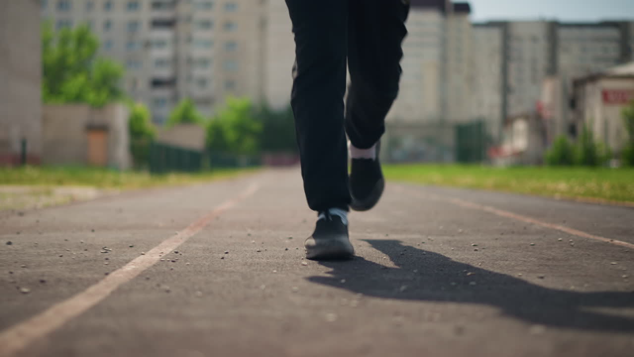 Un hombre caucásico mantiene el ritmo mientras corre por la ciudad por la mañana; un individuo de ascendencia europea mantiene una velocidad constante durante una sesión de jogging urbano a primera hora de la mañana en el entorno de la ciudad.
