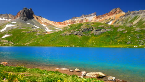 Ice-Lake-Basin-stunning-bright-blue-alpine-above-treelined-clear-water-summer-blue-sky-Rocky-Mountain-snow-range-peaks-Silverton-Telluride-Colorado-dreamy-peaceful-wildflowers-camping-pan-left-motion