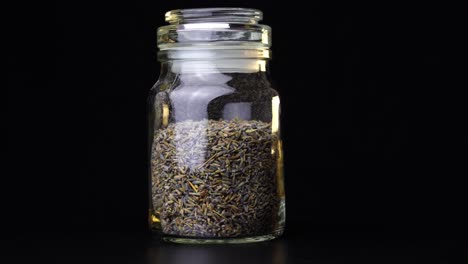 lavender flowers in a glass against a black background