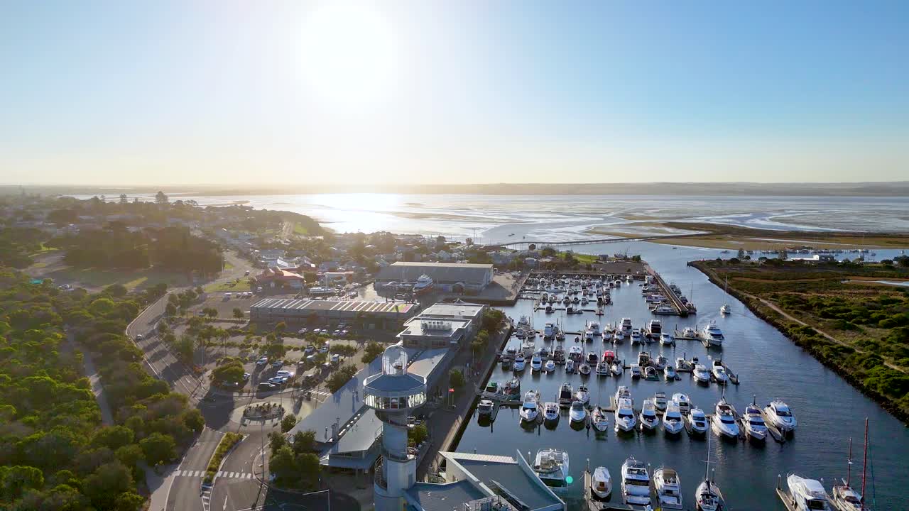 Drone captures serene marina and lush landscape in Bellarine, Victoria, during sunrise. Calm waters and vibrant greenery create a tranquil scene