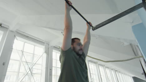 sportsman with prosthetic leg doing hanging leg raise on bar