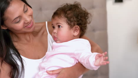 mother with cute baby sitting on bed