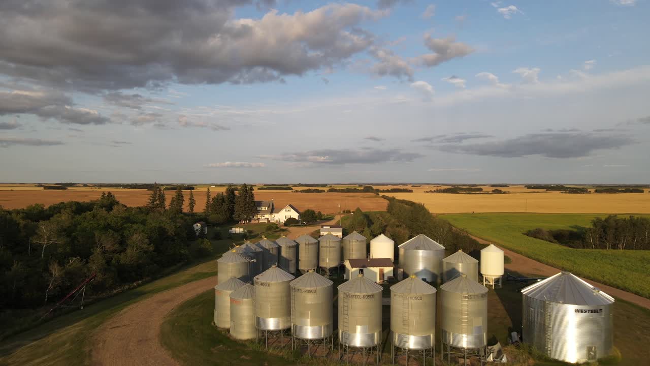 Aerial forward moving drone footage high above a small family operated grain farm in American prairie during sunset