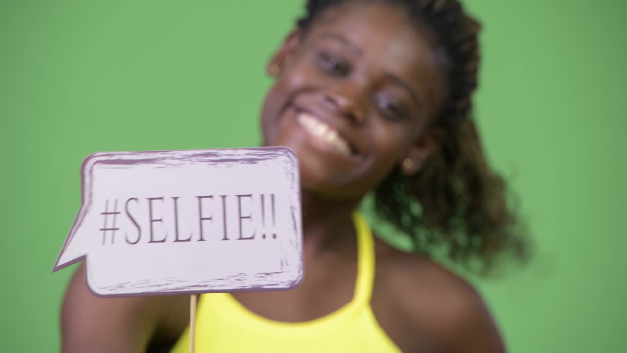 Young African woman showing selfie paper sign