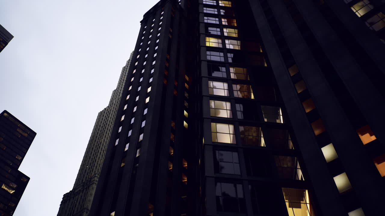 Tall buildings with bright windows reflecting in evening light