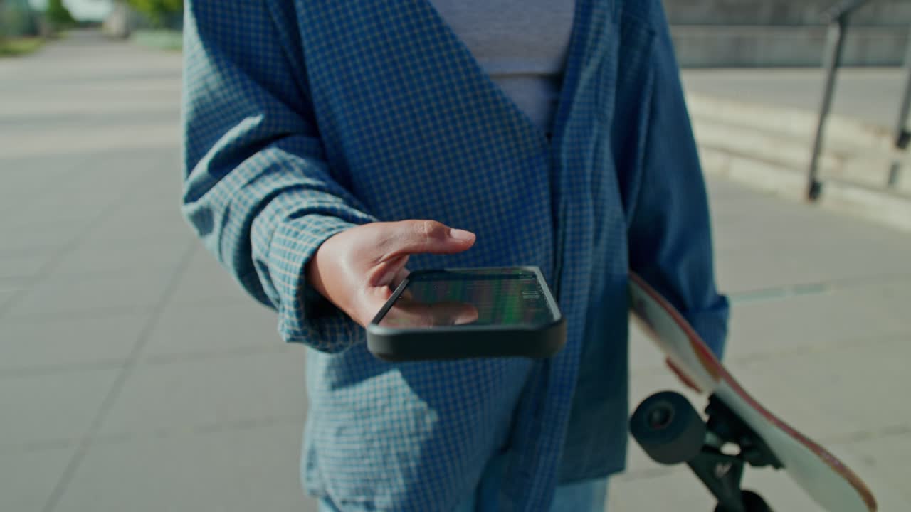 Persona che usa il telefono con lo skateboard