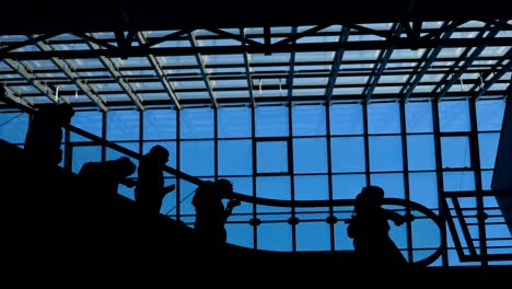 la escalera del aeropuerto de la ventana de vidrio con silueta en movimiento de personas