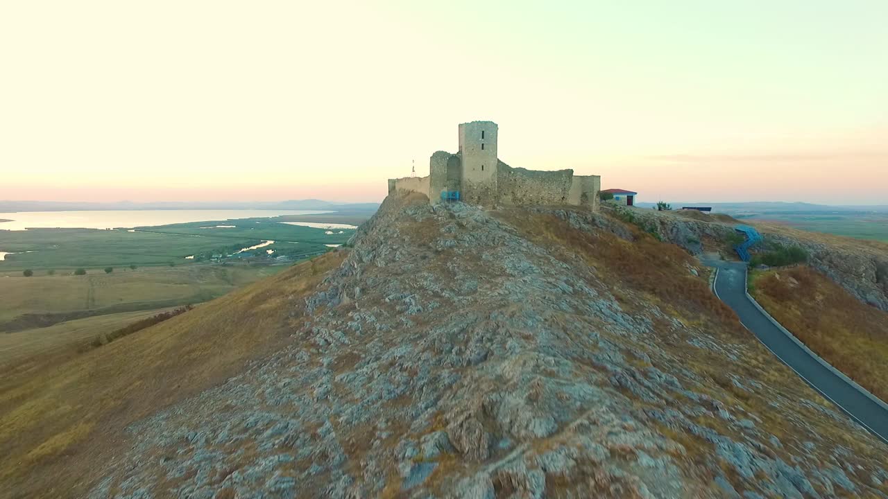 fortaleza de enisala en rumania, disparo de drones, volando hacia la fortaleza al atardecer