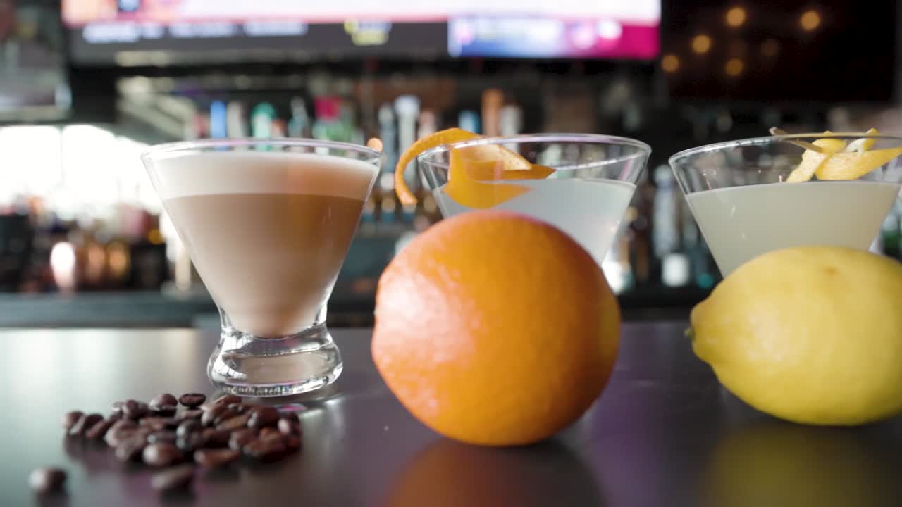 Elegant row of martini cocktails, each garnished with different fruits, showcasing colorful, stylish cocktails in a bar setting